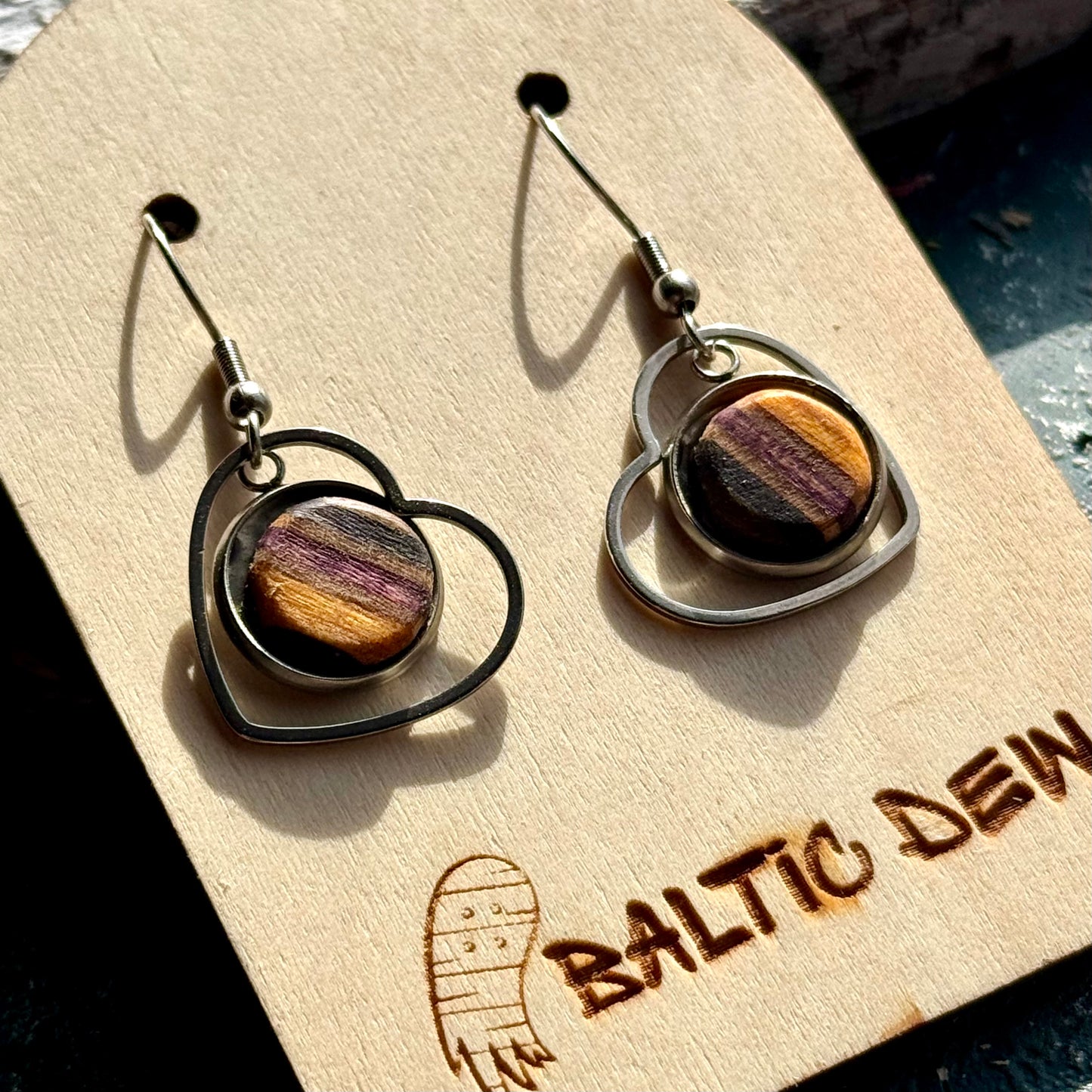 Round drop earrings with dark layered skateboard wood inlays set inside open metal frames.