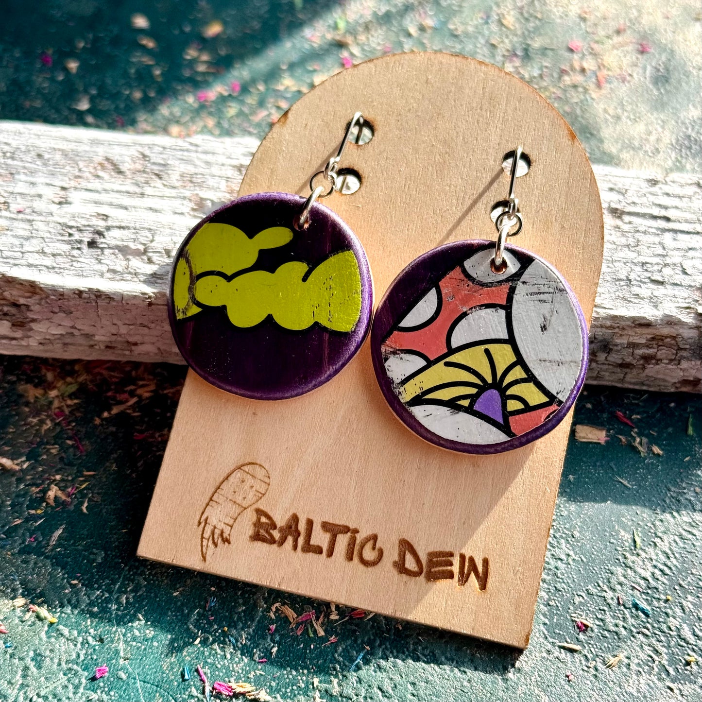 Round purple mushroom and cloud skateboard wood earrings on surgical steel hooks, shown on a card
