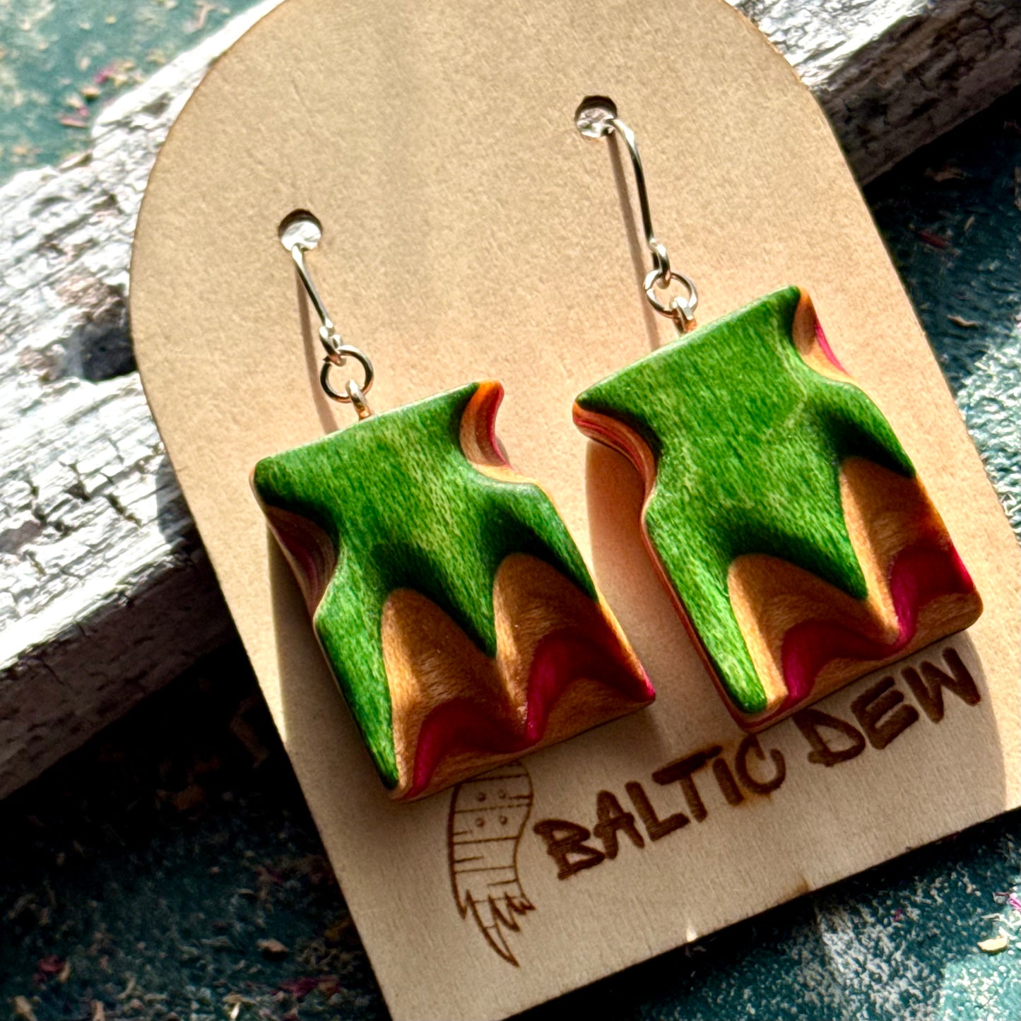 Close view of green, orange and pink skateboard wood wave earrings, handmade by Baltic Dew