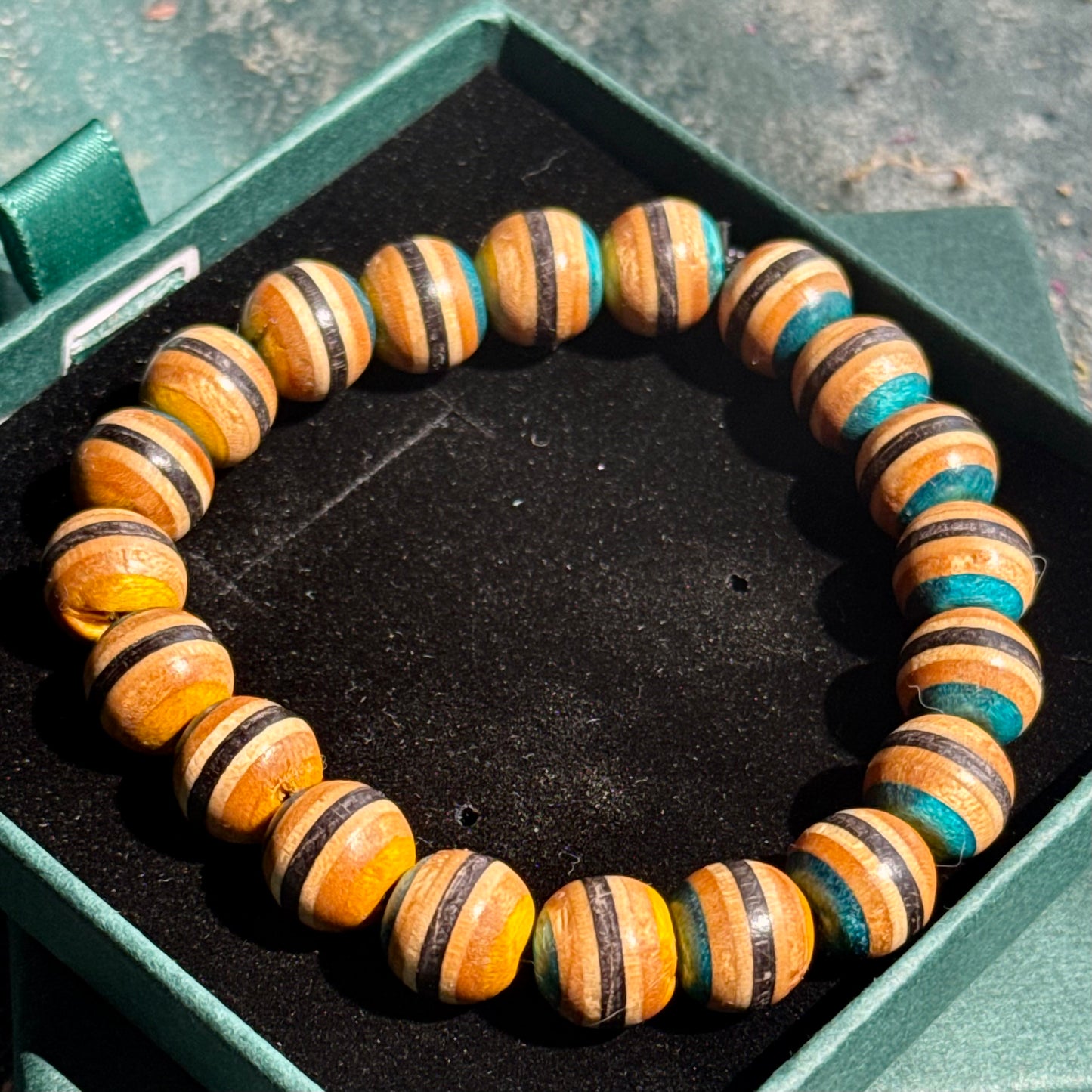 Close-up of a Yellow and Blue Skateboard Bracelet made from recycled skateboard wood beads with natural and painted stripes.