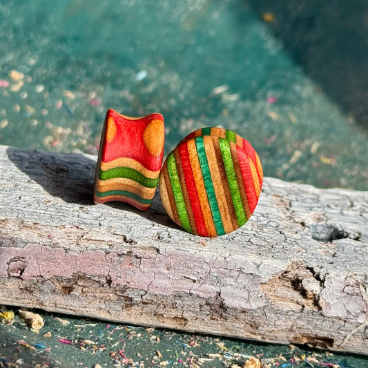 Green, Red and Orange Double Flare Wooden Ear Plugs 16mm with striped vibrant color pattern on wood surface.