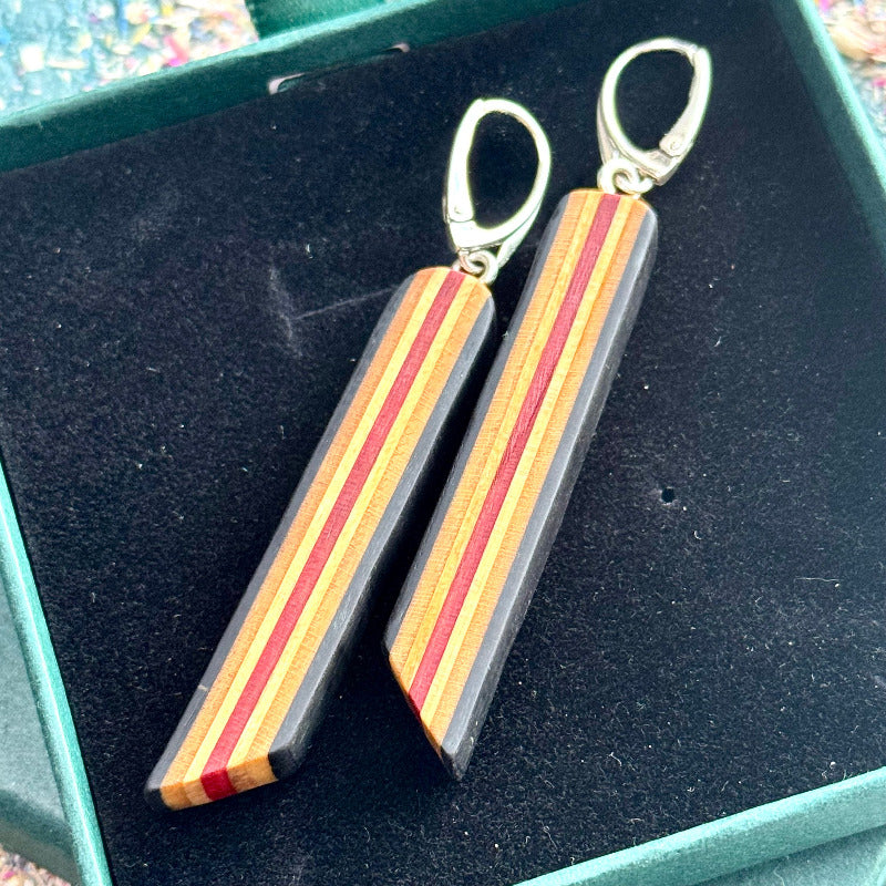 Wooden earrings with red and black stripes on a dark surface