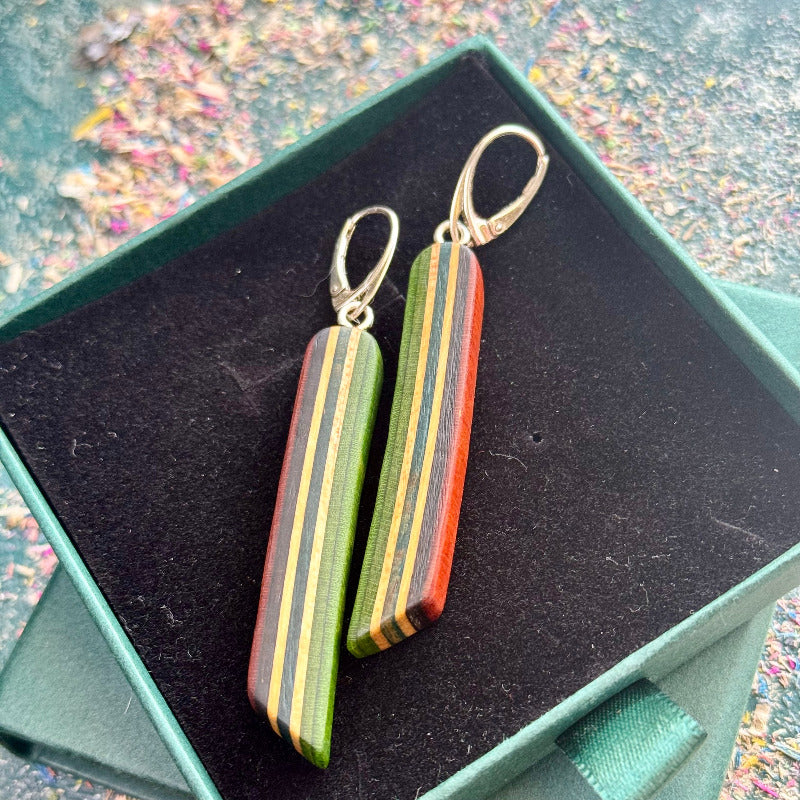 Colorful striped earrings in a green box with a multicolored background