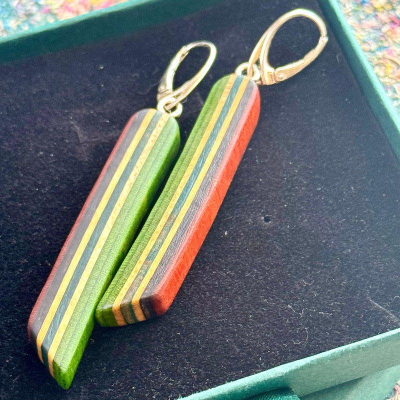 Wooden earrings with gold hooks on a dark surface
