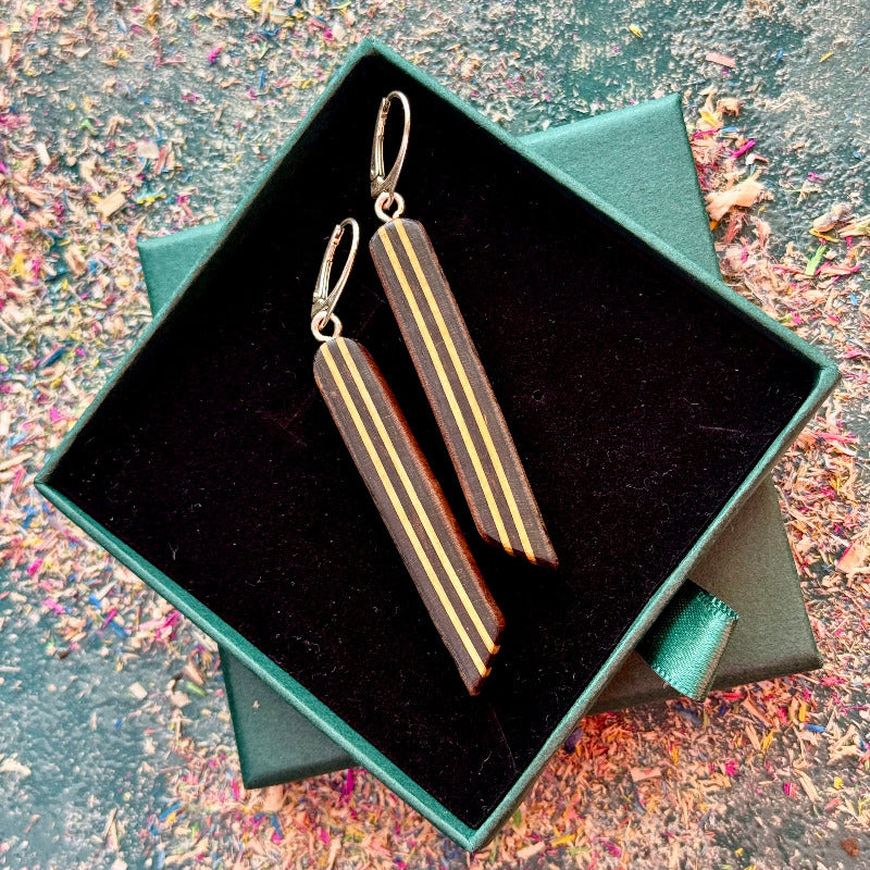 Pair of earrings in a green box on a textured surface