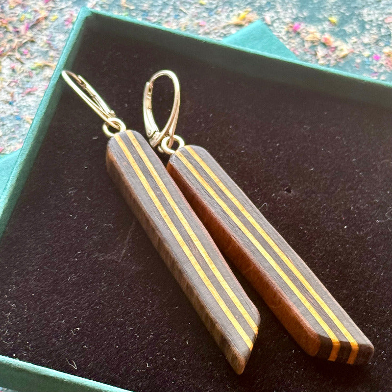 Wooden earrings with gold accents on a dark surface