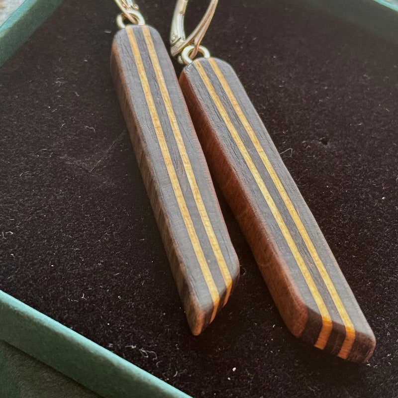 Wooden earrings with striped design on a dark surface