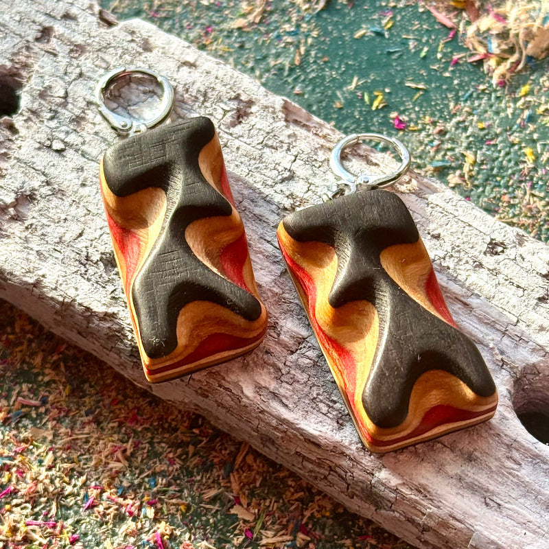 Wooden earrings with a wavy design on a wooden surface