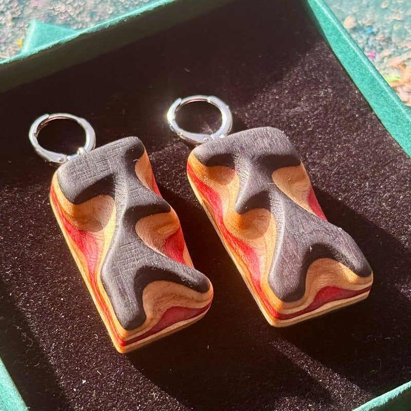 Wooden earrings with a marbled design on a dark surface