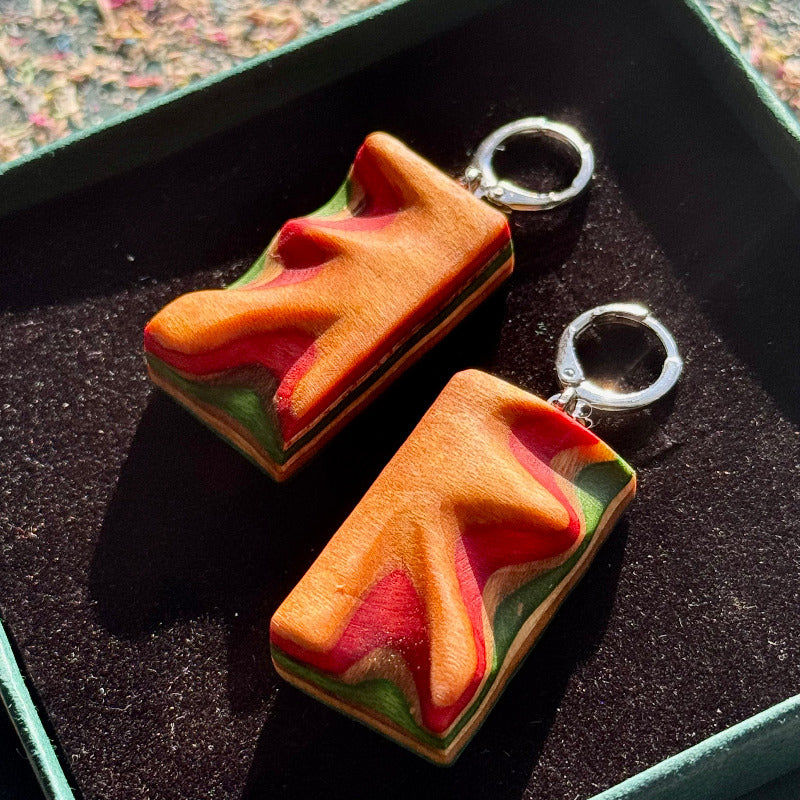 Two colorful keychains shaped like sandwiches on a dark surface.