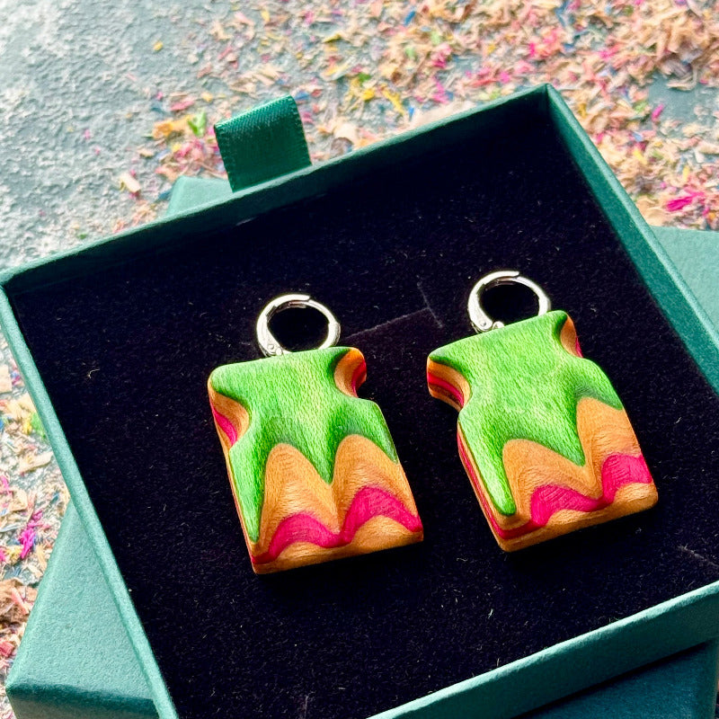 Colorful abstract earrings in a green box with a colorful background
