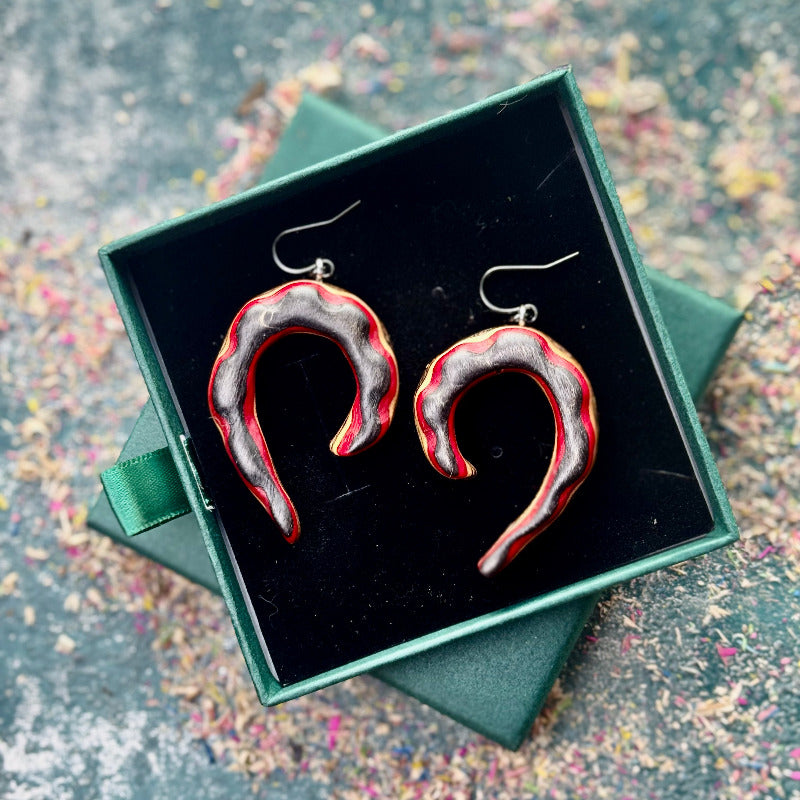 Heart-shaped earrings in a green box on a textured surface