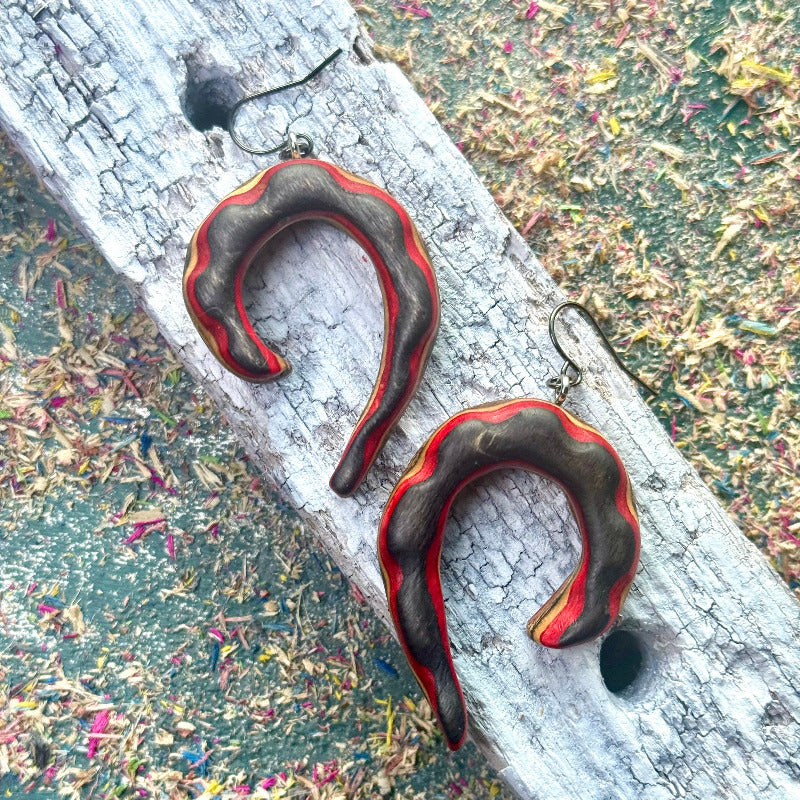 Pair of black and red earrings on a textured surface
