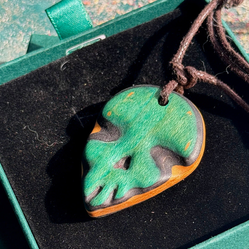 Wooden heart-shaped pendant with green and brown colors on a dark background