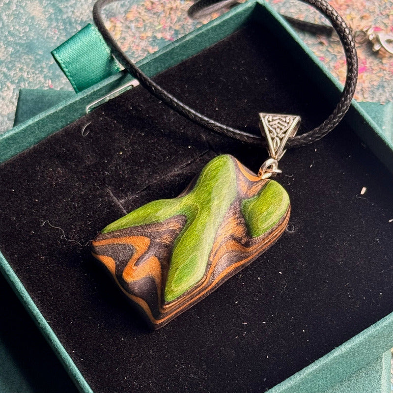 Heart-shaped green and brown pendant with a silver triangle on a black background