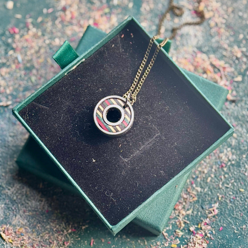 Necklace with a circular pendant on a black box with a textured surface