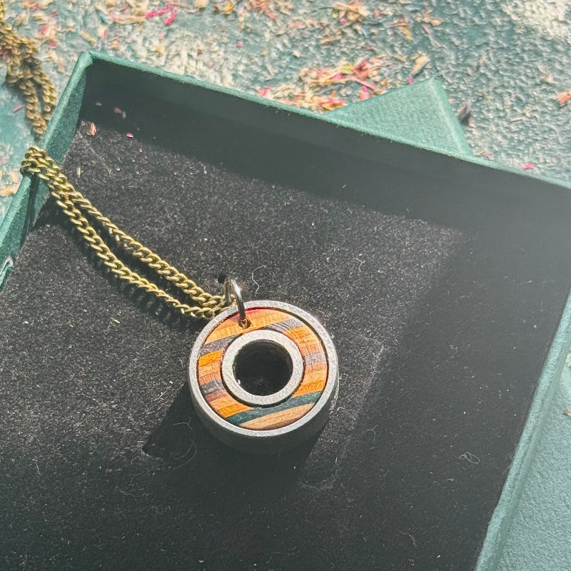 Wooden pendant necklace on a black surface with a green box