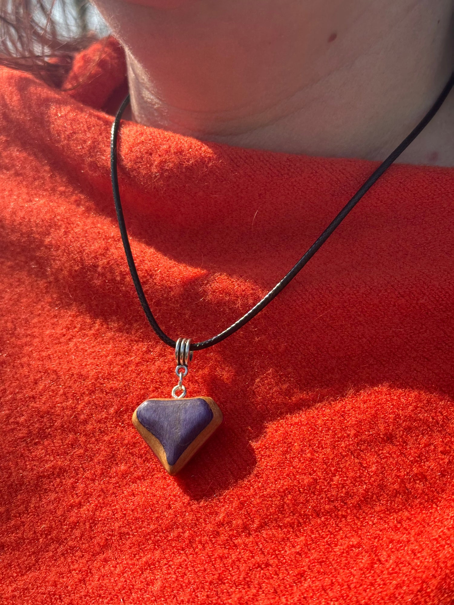 diamond-shaped recycled skateboard pendant on faux leather cord, worn around the neck in natural light.