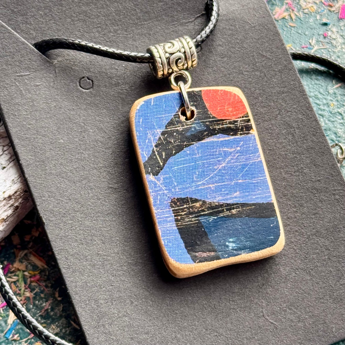 Recycled skateboard wood pendant with a blue face, orange disc and natural maple edges.