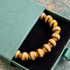 Yellow and black recycled skateboard wood bead bracelet in its gift box, photographed outdoors