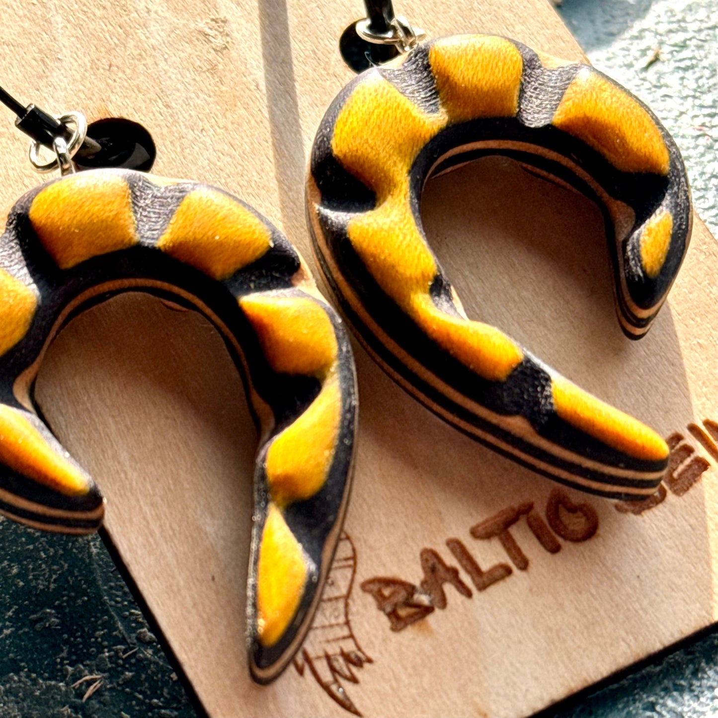 Yellow and black skateboard wood spiral earrings, carved so the maple layers follow the curve