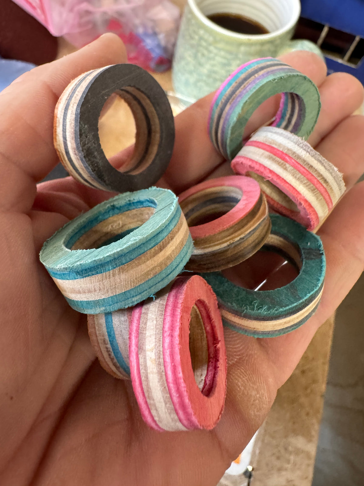 Roughly cut recycled skateboard wood ring pieces in pink, teal and green, before shaping on the lathe.