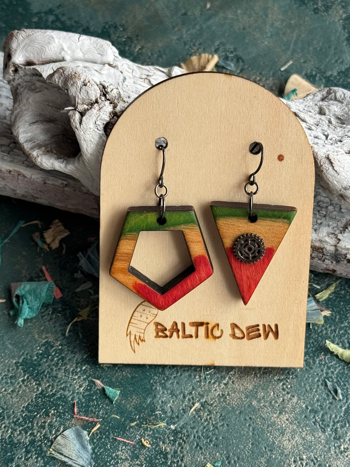 Mismatched skateboard wood earrings, a green pentagon outline paired with a red triangle