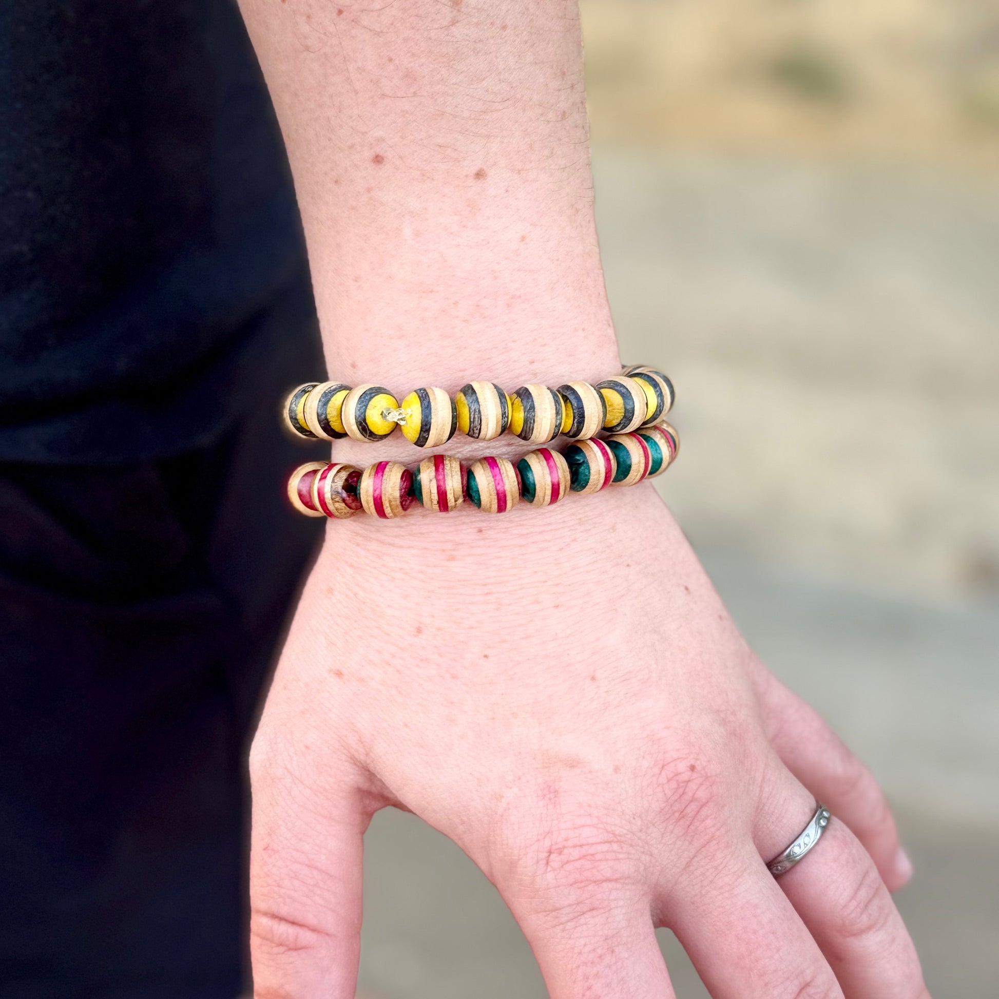 Pink and green recycled skateboard wood beaded bracelet worn on the wrist