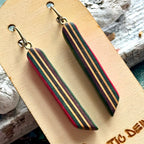 Close view of pink, teal and purple striped skateboard wood long drop earrings, handmade by Baltic Dew