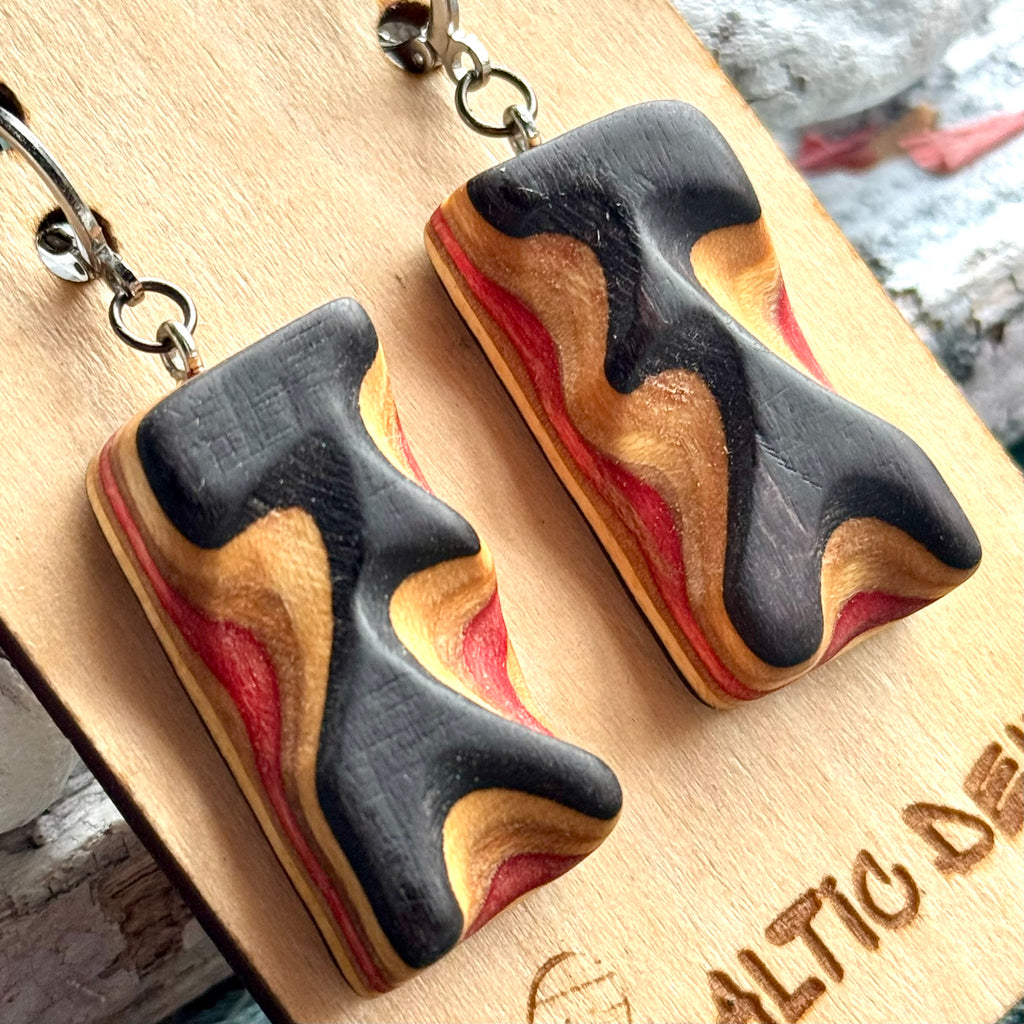 Close view of black and red banded wave earrings cut from recycled skateboard maple