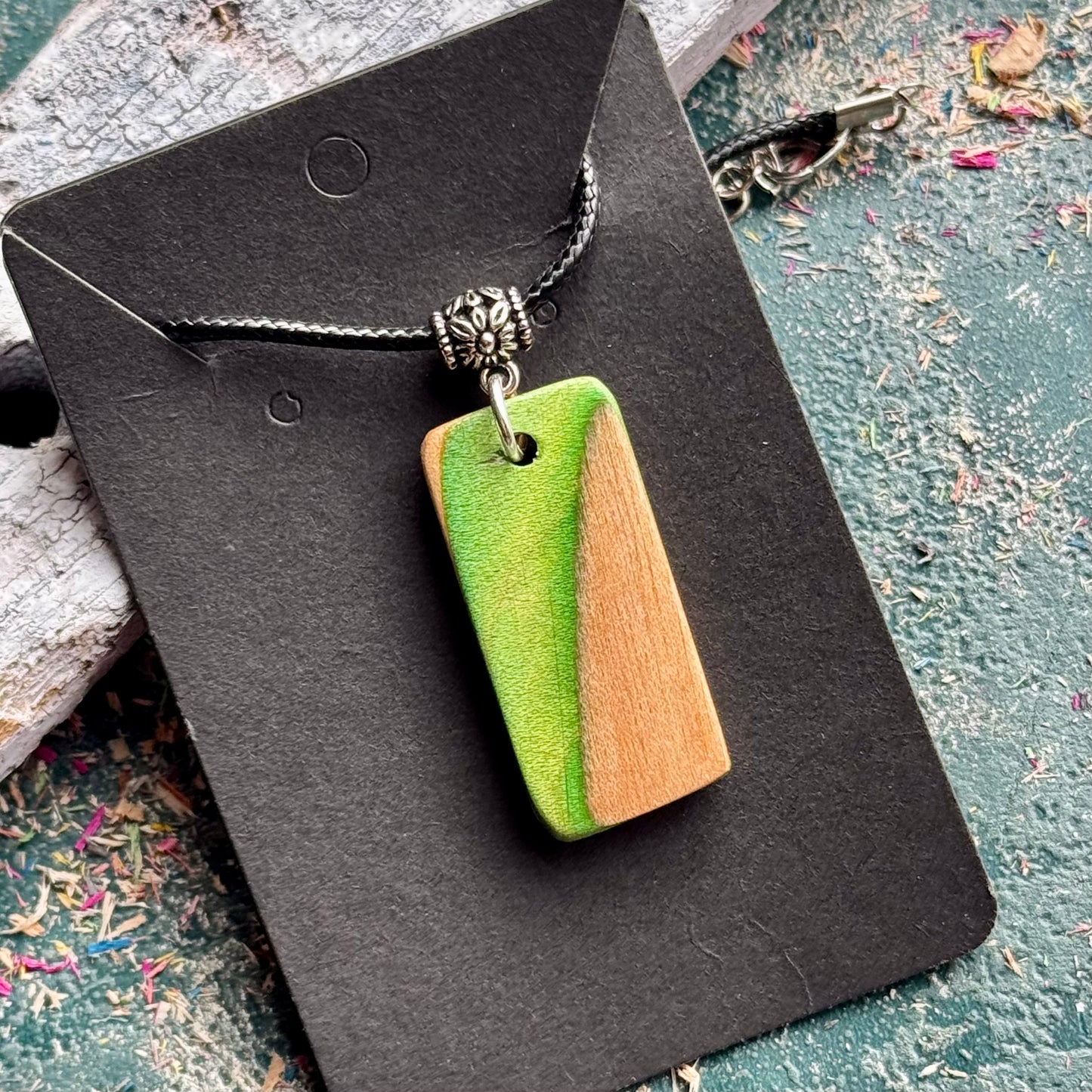 Recycled skateboard wood pendant showing the green deck layer against the natural maple grain.