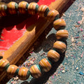 Close-up of yellow and light teal layers on beads cut from a recycled skateboard deck, handmade by Baltic Dew.