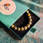 Black, yellow and green striped maple beads from a recycled skateboard deck, strung on elastic cord.