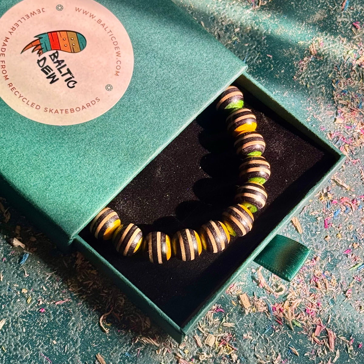 Black, yellow and green striped maple beads from a recycled skateboard deck, strung on elastic cord.