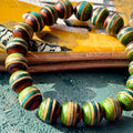 Recycled skateboard wood bracelet showing green, teal and brown deck layers against natural maple.
