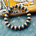 Blue and black wood bead bracelet from recycled skateboard maple in a full round on a yellow skateboard deck.