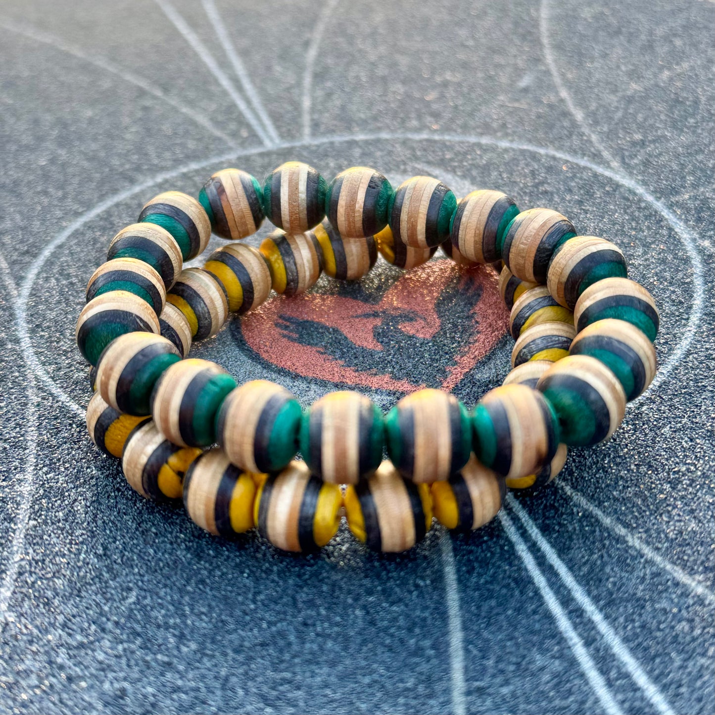 Recycled skateboard wood beaded bracelet photographed on a skatepark surface
