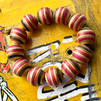 Chunky red, pink, black and teal recycled skateboard bracelet on a yellow printed deck, handmade by Baltic Dew.