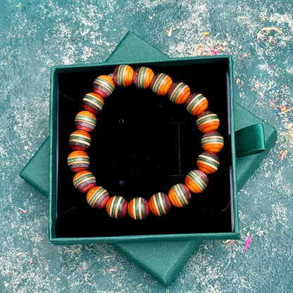 Orange, green and red wood bead bracelet from recycled skateboard maple, shown from above in its green gift box.