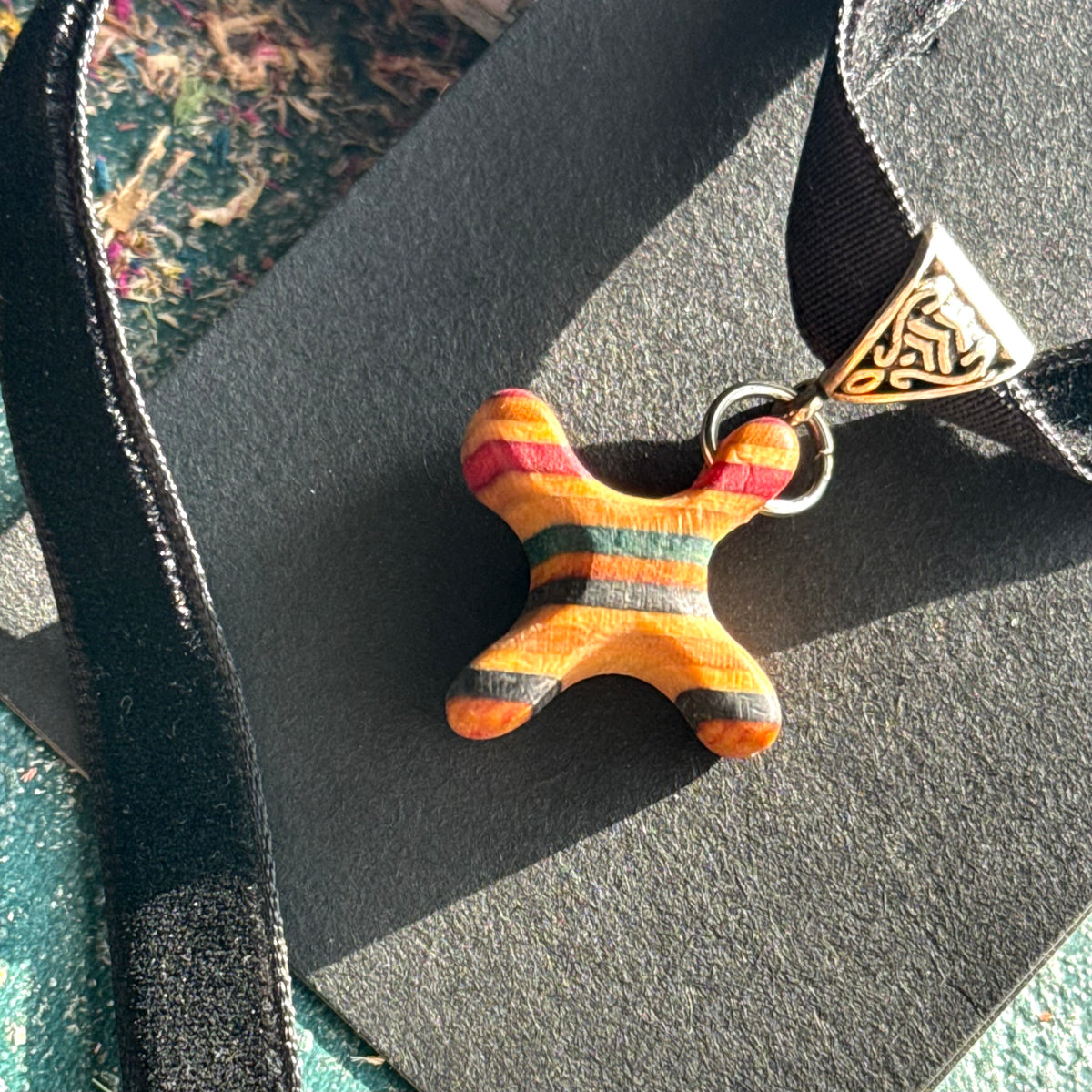 Rainbow striped cross pendant in recycled skateboard maple on a black velvet choker, handmade by Baltic Dew.
