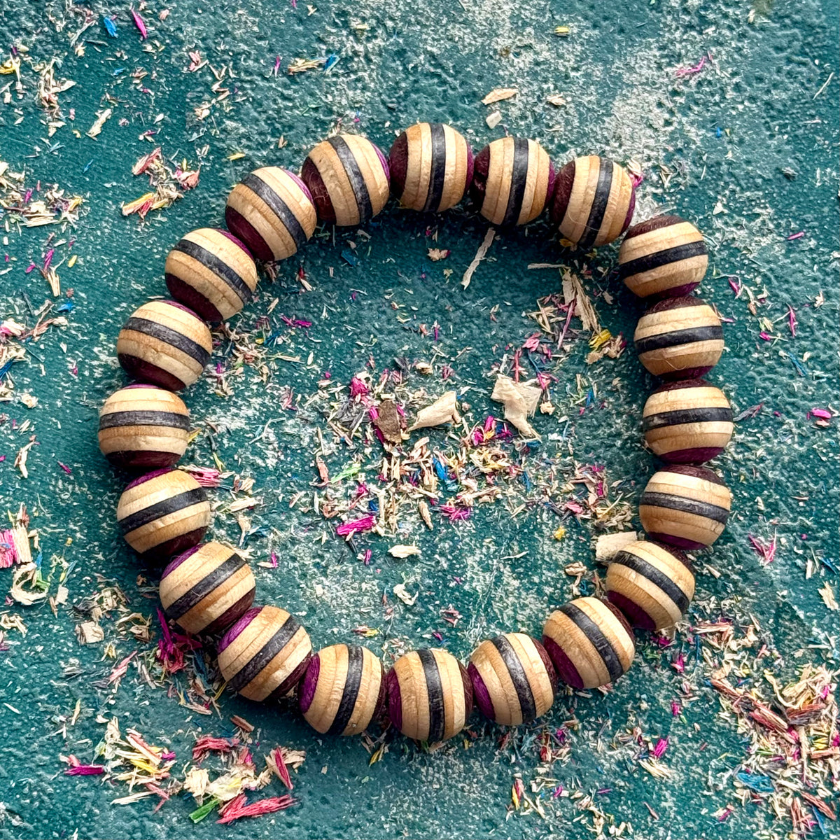 Purple, brown and black striped maple beads from a recycled skateboard deck, strung on elastic cord.