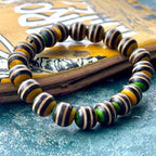 Recycled skateboard wood bracelet showing black, yellow and green deck layers against natural maple.