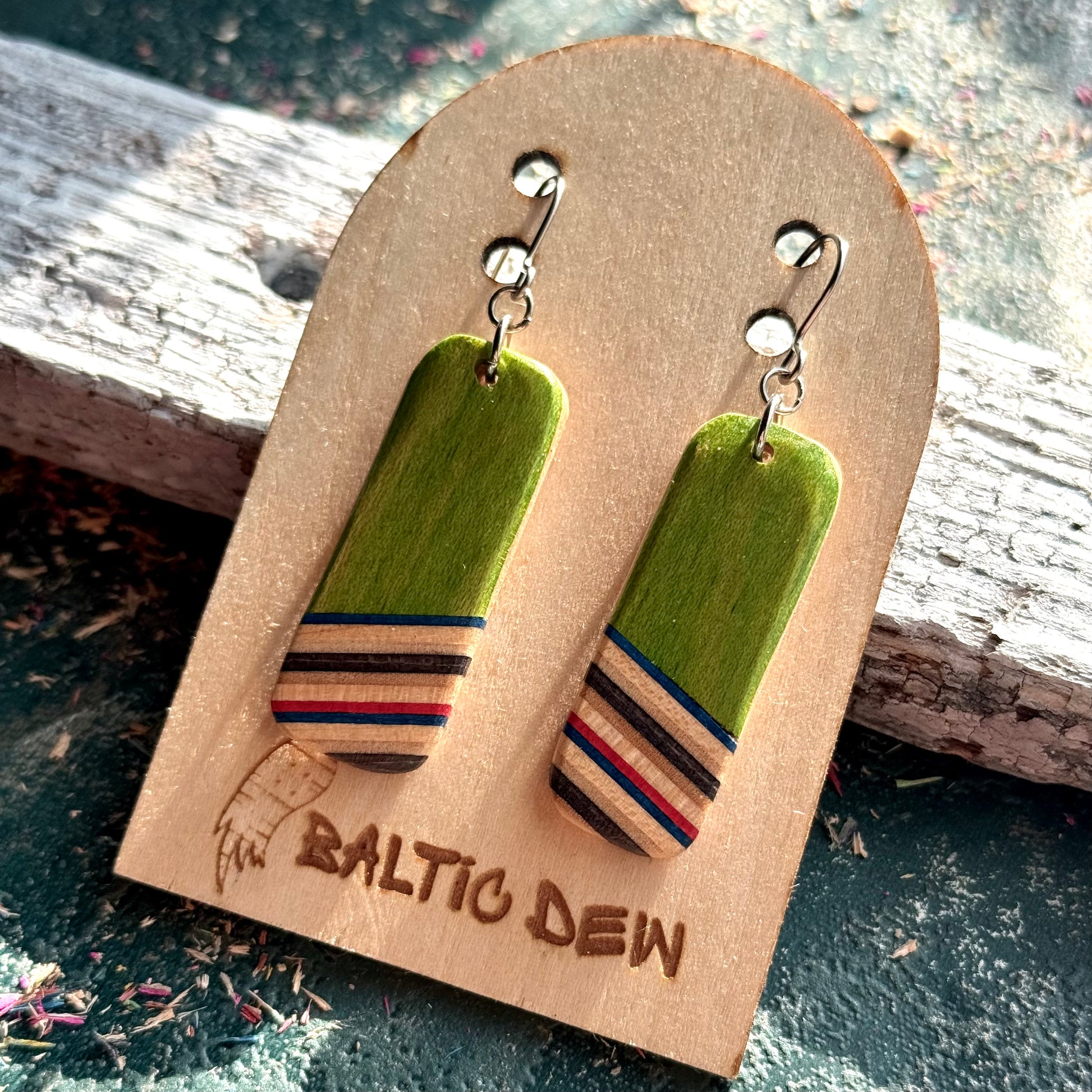 Green recycled skateboard rectangle drop earrings with pink, natural maple and dark colour layers.
