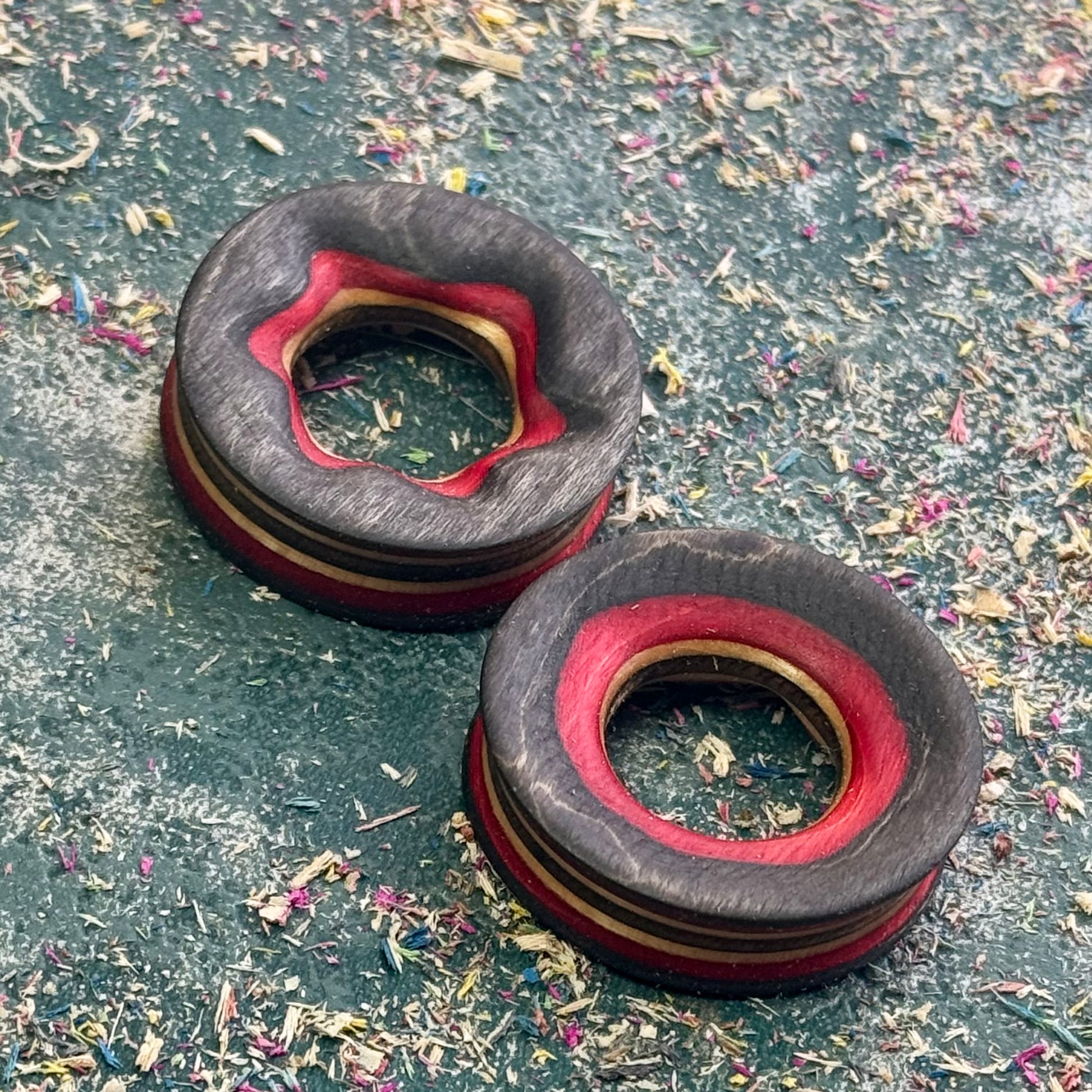 Dark grey tunnels with a red inner edge, cut from the darker layers of a recycled deck.