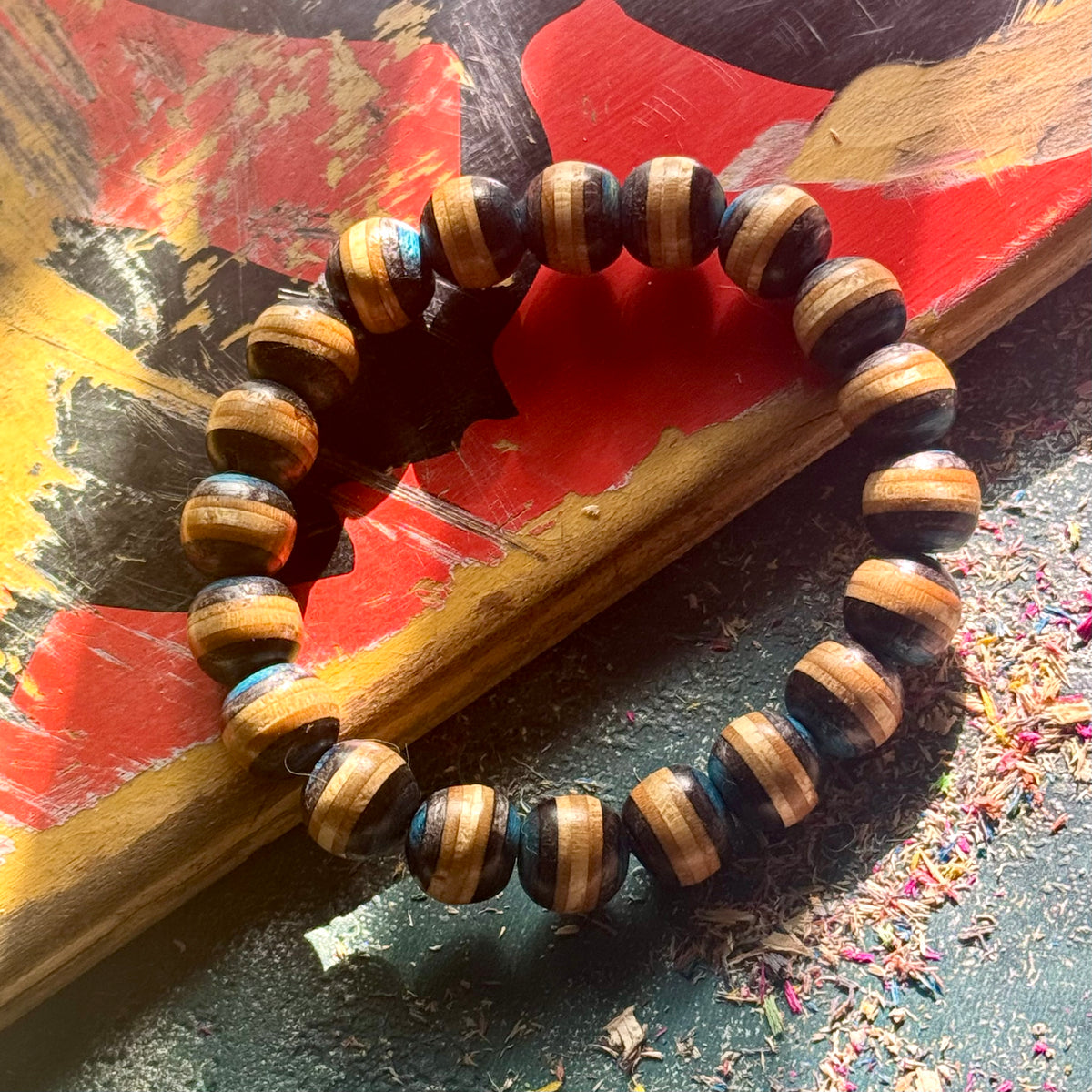 Blue and black recycled skateboard wood bead bracelet on a painted skateboard deck.