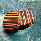 A pair of ear plugs in red, yellow and black skateboard maple, stripes running across the face.
