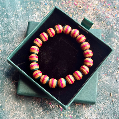 Pink and Teal Skateboard Bracelet made of round beads with alternating pink and teal stripes displayed in a green presentation box.