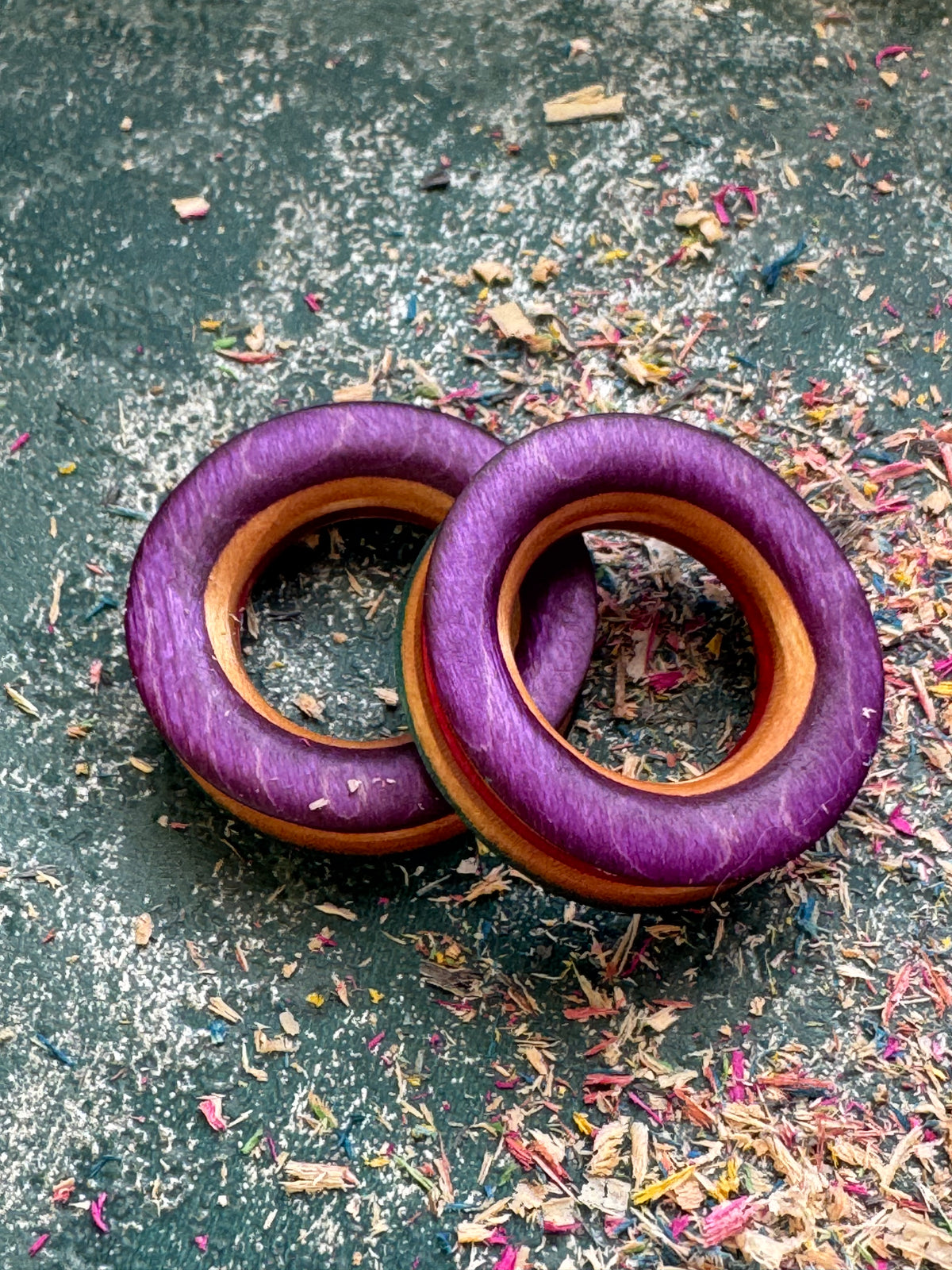 Pair of purple skateboard wood tunnels with natural maple showing around the bore.