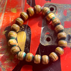Light teal and yellow recycled skateboard bracelet on a red deck with an old truck baseplate, handmade by Baltic Dew.