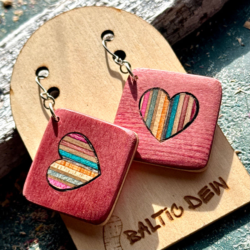 Dusty pink recycled skateboard square drop earrings with heart cut-outs, showing turquoise, orange and pink layers.